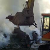 A earthdigger relocates hundreds of cattle and sheep infected with foot-and-mouth disease as they are being incinerated (pic: Getty Images)