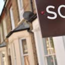 An estate agent's "sold" board stands outside a residential building.