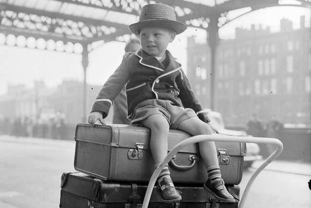 Three-year-old Paul Flannigan sits on top of the luggage ready to go on holiday at Glasgow Central Station in 1957.