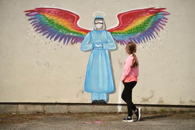 A girl looks at a mural by artist Rachel List paying tribute to NHS staff battling the COVID-19 outbreak painting on a wall in Pontefract (Photo: OLI SCARFF/AFP via Getty Images)