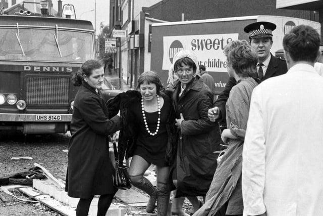 A distressed woman is helped from the scene at Clarkston Toll in Glasgow, after a faulty gas main exploded killing 20 shoppers and injuring hundreds in October 1971.