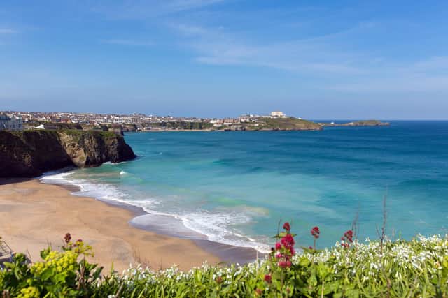 Newquay's Tolcarne beach with blue sky and sea and view towards the harbour