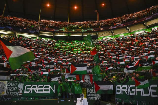 The Green Brigade hold up Palestine flags during a Champions League match against Atletico Madrid.