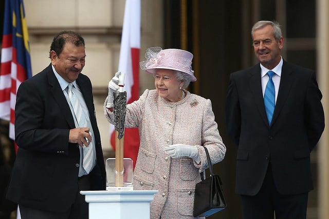 Queen Elizabeth II places a message for the host city in the Queen's Baton as HRH Prince Imran, President of the Commonwealth Games Federation (L) and Rt Hon Lord Smith of Kelvin, Chairman of the Glasgow 2014 Organising Committee (R) watch on.