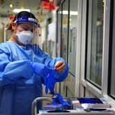 A nurse puts on PPE in a ward for Covid patients at King's College Hospital, in south east London. Picture date: Tuesday December 21, 2021.