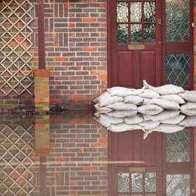 Sandbags outside front door of flooded house. Photo: Adobe
