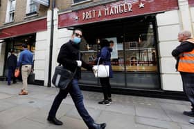 A man wearing PPE (personal protective equipment) passes customers queuing to enter a recently re-opened Pret-A-Manger shop which had originally closed-down due to the COVID-19 pandemic in London (Photo: TOLGA AKMEN/AFP via Getty Images)