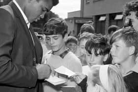 Boxer Muhammad Ali signs autographs for children on his arrival in Glasgow in 1965.