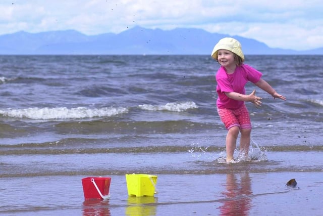 Ayr beach on the first week of Glasgow Fair Fortnight in 2000, with three-year-old Jade Henderson of Robroyston splashing in the Firth of Clyde with the Isle of Arran in the background.