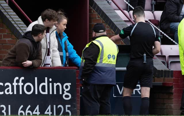 Referee Don Robertson checks the VAR monitor for a handball by Celtic's Tomoki Iwata.