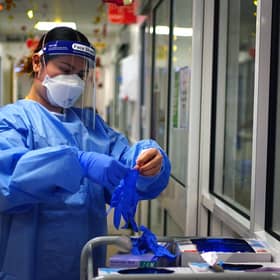 A nurse puts on PPE in a ward for Covid patients at King's College Hospital, in south east London. Picture date: Tuesday December 21, 2021.