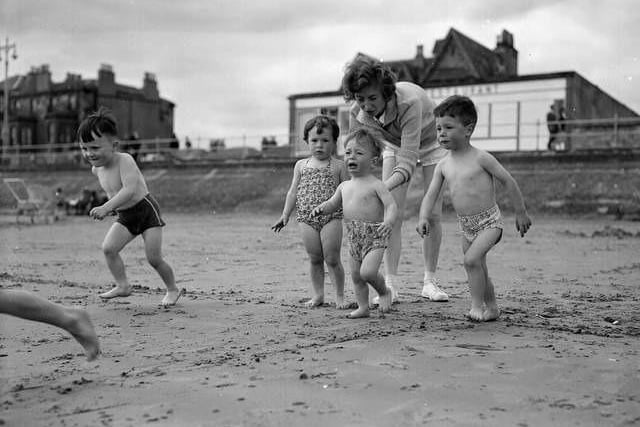 A mother persuades her little boy to go into the sea at Portobello Beach during the fair fortnight in 1961.