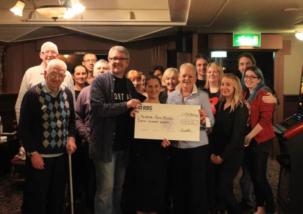 CHEQUE HANDOVER: Quizmaster David Weatherstone and manager Maureen Mitchell hand over the cheque to SSBA community fundraiser Lynsey Hamilton, watched by pu b regulars.