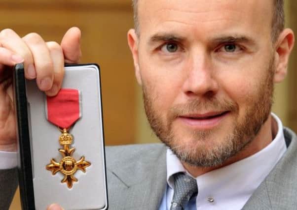 British musician Gary Barlow poses with his badge after being made an Officer of the Order of the British Empire (OBE) for services to music by Britain's Queen Elizabeth II at an investiture ceremony at Buckingham Palace in central London on November 21, 2012. AFP PHOTO / POOL / JOHN STILLWELL (Photo credit should read JOHN STILLWELL/AFP/Getty Images)