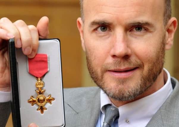 British musician Gary Barlow poses with his badge after being made an Officer of the Order of the British Empire (OBE) for services to music by Britain's Queen Elizabeth II at an investiture ceremony at Buckingham Palace in central London on November 21, 2012. AFP PHOTO / POOL / JOHN STILLWELL        (Photo credit should read JOHN STILLWELL/AFP/Getty Images)
