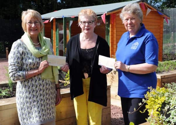 Cheque this...Isobel Watson (left) of the playpark action group and Sylvia Russell (right) of the trust restoring Castlebank in Lanark, receive cheques from Margaret Seymour. (Pic Alan Watson)