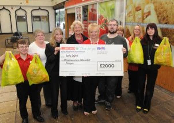 Shop Manager Jennifer Stewart (third left) and staff hand over the cheque to Abronhill Regeneration Forum.