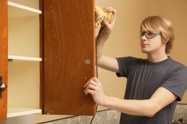 A man building a storage cupboard in the kitchen.