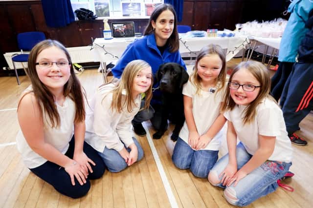 The Clarkston girls meet Cracker, a guide dog in training, and hand a charity cheque over to Wendy Kinnin. Photo by Jane Henderson.