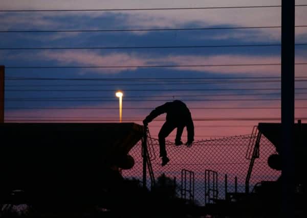 Refugee climbs a fence in Calais