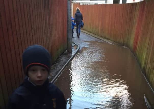 Elliot Miller and his mum have to negotiate the flooded path on the way to school.