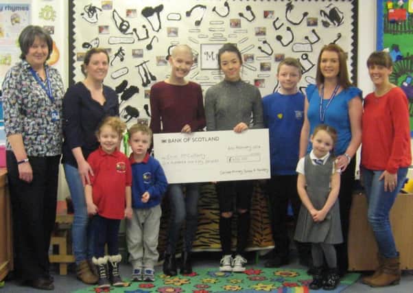 Carluke Primary and nursery pupils present a cheque to Erin McCafferty and twin sister Nicole.