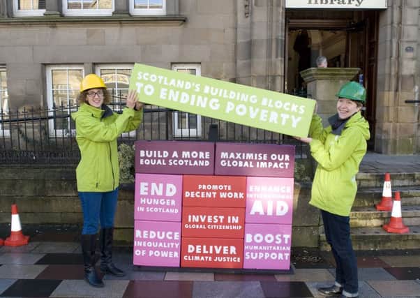 Oxfams Lisa Stewart and Suzanne Crimin give the Scottish Parliament a clear message as they build a five-foot high wall outside Motherwell Library.