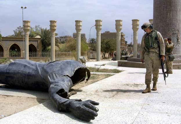 US Marines walk pass a dismounted statue of Saddam Hussein on Baghdad's al-Fardous square 10 April 2003. As the regime of Saddam Hussein collapsed, questions marks hung 10 April, 2003 over the fate of Saddam Hussein and the task of rebuilding Iraq. Despite almost universal euphoria at the downfall of Saddam, symbolised by the toppling 09 April of a huge statue of the Iraqi leader, the United States and its key ally Britain warned the 22-day war was not at an end. So far, US forces suffered at least 101 dead, their British allies about 30. Thousands of Iraqis are believed to have been killed. AFP PHOTO  PATRICK BAZ        (Photo credit should read PATRICK BAZ/AFP/Getty Images)