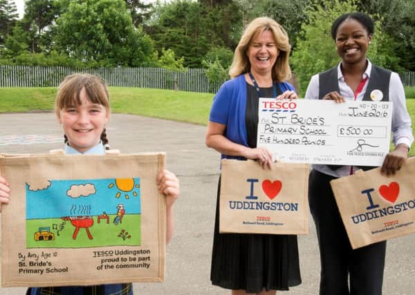 St Bride's Primary pupil Amy Gray shows off her winning design with head teacher Denise Pacitti and Tesco customer experience manager Bukky Olu.