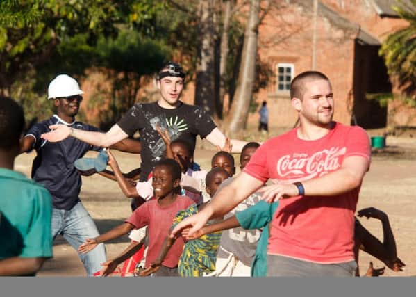 Volunteers and children practise dance moves in Malawi.
