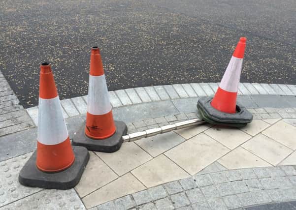 Traffic cones have been placed around the flattened safety bollard