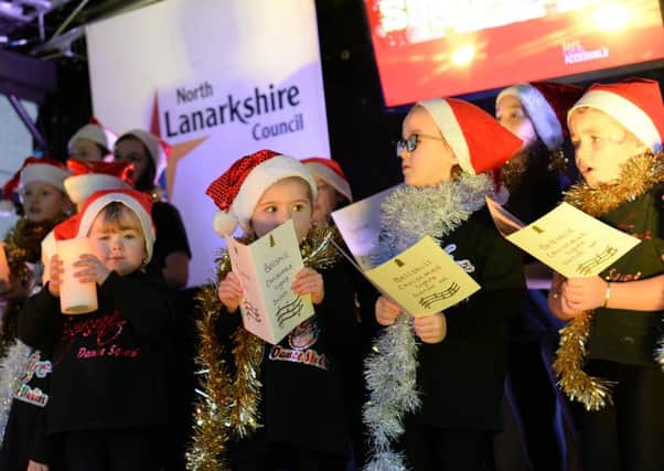 Carol singers get into the Christmas spirit as festive lights are switched on.