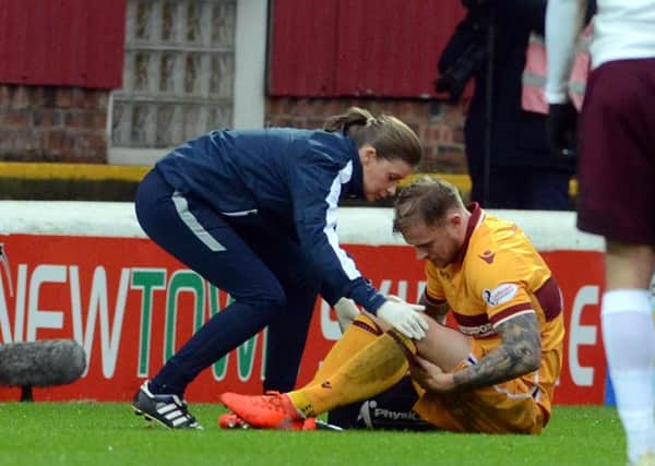 Richard Tait receives treatment from Motherwell physio Aileen Anderson shortly before limping off against Hearts in Motherwell's last game (Pic by Alan Watson)