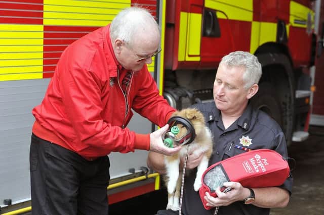 Bishopbriggs Fire Station - firefighter Alan Rutherford and Ron Ewing from Smoky Paws with dog Katie wearing one of the masks.
