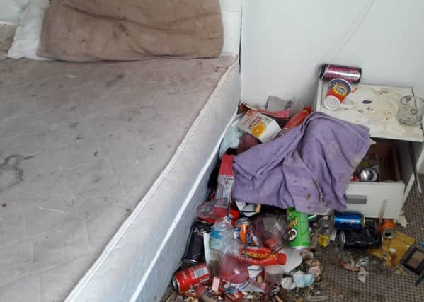 A pile of rubbish, food and other debris down the side of a soiled bed in the flat.