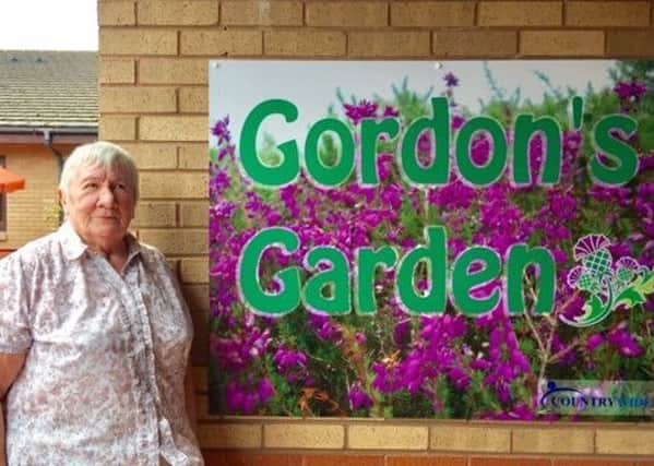 Elizabeth Williamson at the sign for the garden named after her husband Gordon
