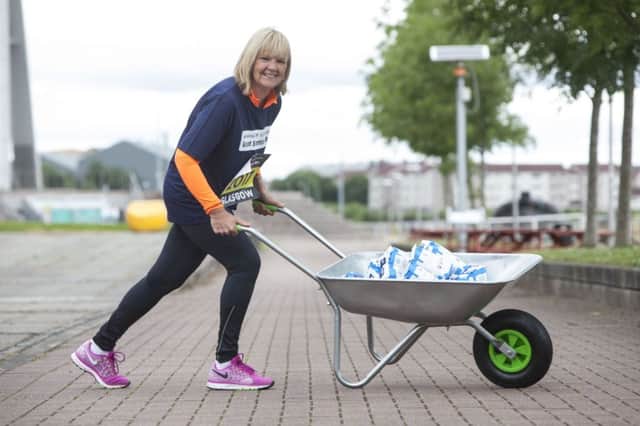 Wendy pushes a wheelbarrow containing the equivilent of her weight loss in bags of sugar