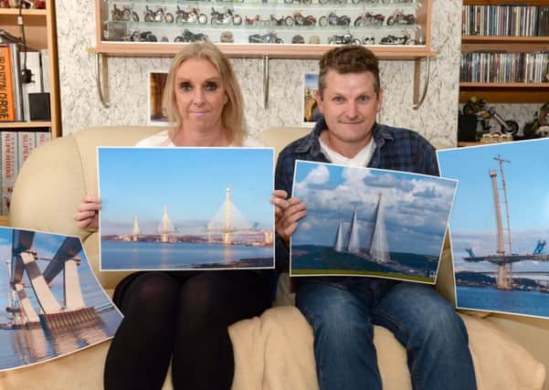 Karen and Alan McRobert show off some of the pictures he took during their trips to watch the construction of the Queensferry Crossing. Pic: Alan Watson