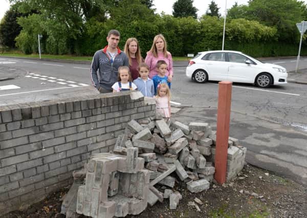 Scott and Louise Anderson and Chelsey Marks (right) and their children at the section of garden wall damaged in the second crash last week. Pic: Alan Watson