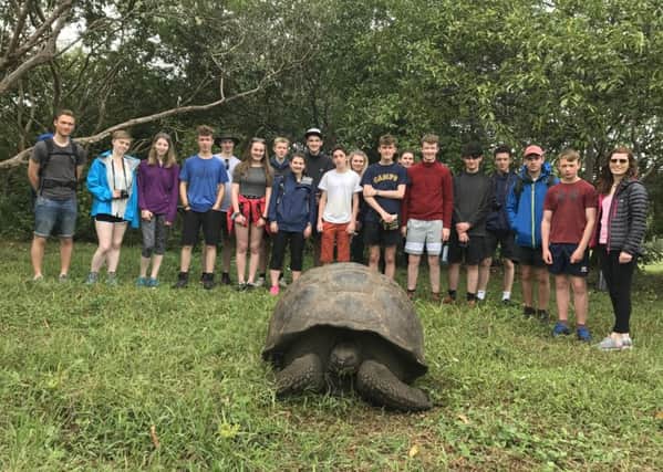 Students posing behind one of the worlds longest-lived vertebrates, the Galapagos Giant Tortoise.