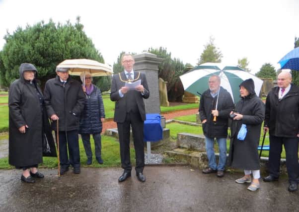 Provost Ian McAllan unveils the plaque in Lanark cemetery, across from the original monument.