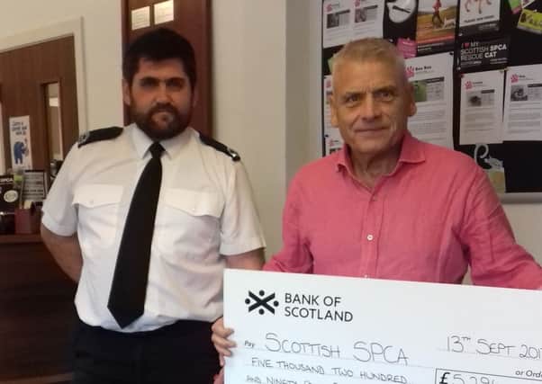 Edinburgh SSPCA centre assistant manager Kenny Sharpe receives a cheque from Tom Renton from Calzeat.