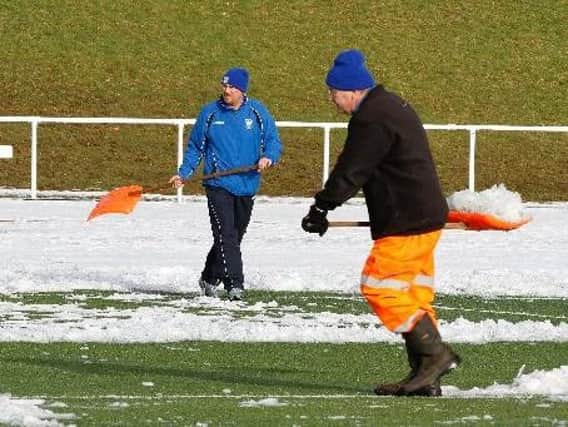 Snow is cleared off the John Cumming Stadium pitch by volunteers before a Carluke Rovers match two years ago (Library pic)