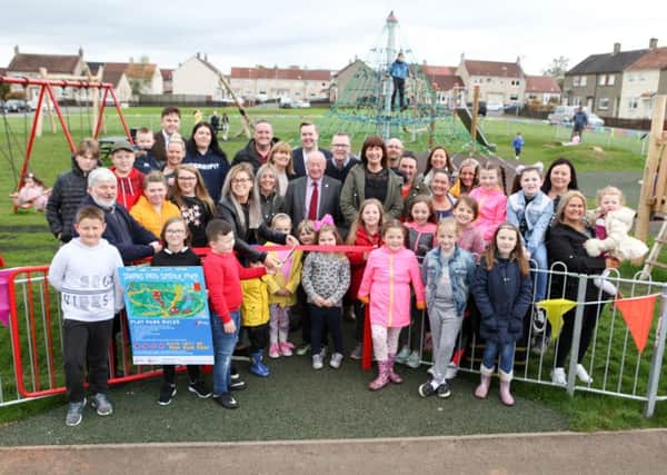 Competition winner Jayden Young cuts the ribbon while Annalise Gribbon holds up the sign they designed for the play area