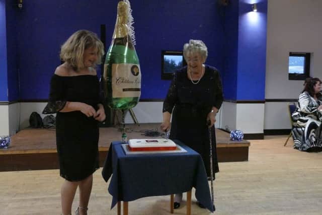 Chair Glynis Poole and longest serving member Margaret Tomlinson cutting the cake.