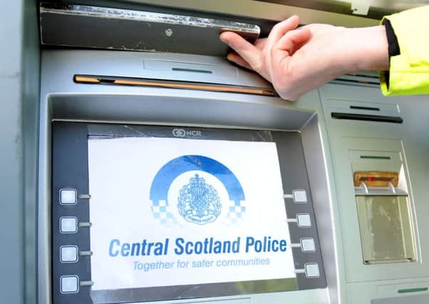 Police doing a credit card skimming demonstration with devices to help warn public of dangers a officer shows where the small video camera would be placed on a cash machine