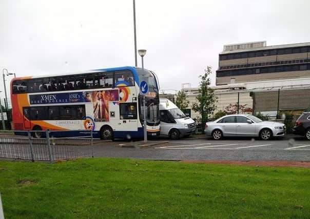 A bus has to mount the traffic island to get past parked cars in North Carbrain Road
