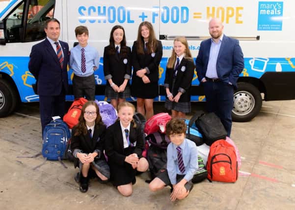 Adam Clark, group business sales and development director at Arnold Clark, and Daniel Adams, executive director of Marys Meals UK, join pupils supporting to the charitys Backpack Project helping children in Malawi.